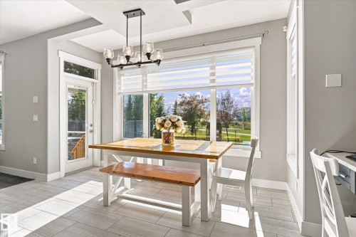 Recessed ceiling details, large picture window with blinds, modern multi-bulb chandelier, and tiled flooring - 2011 Genesis Lane, Stony Plain, AB 