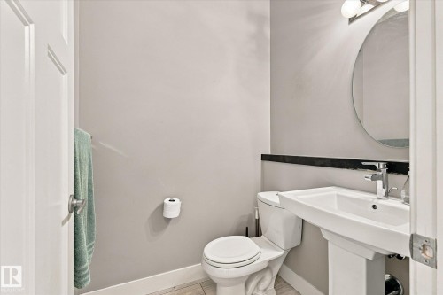 Pedestal sink with chrome faucet, circular wall mirror, and modern vanity lighting - 2011 Genesis Lane, Stony Plain, AB 