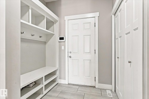 Built-in storage bench with open shelving, wall-mounted coat hooks, and multi-panel doors - 2011 Genesis Lane, Stony Plain, AB 
