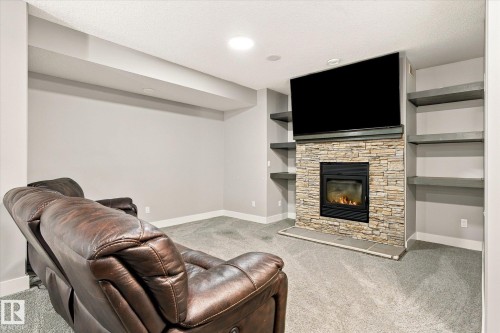 Recessed lighting, built-in shelving, stone-faced fireplace with hearth, and carpeted flooring - 2011 Genesis Lane, Stony Plain, AB 
