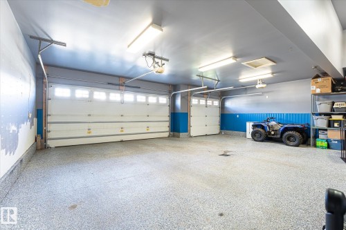 Multi-car garage featuring two overhead garage doors, overhead lighting, and a textured floor finish - 2011 Genesis Lane, Stony Plain, AB 