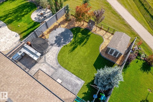 Expansive backyard featuring a built-in outdoor kitchen, paver patio, circular paver hardscaping, manicured lawn, and a storage shed - 2011 Genesis Lane, Stony Plain, AB 
