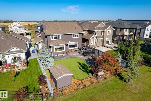 Expansive backyard featuring a manicured lawn, a large paver patio, a utility shed, and mature landscaping - 2011 Genesis Lane, Stony Plain, AB 