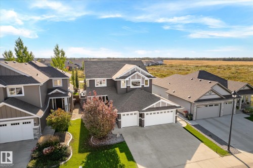 Contemporary two-story residence featuring a two-car garage, dark-toned siding with white trim accents, and a landscaped front yard - 2011 Genesis Lane, Stony Plain, AB 