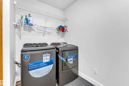 Laundry area featuring a textured gray floor, white walls, and two white wire shelving units - 10621 175A Avenue Nw, Edmonton, AB 