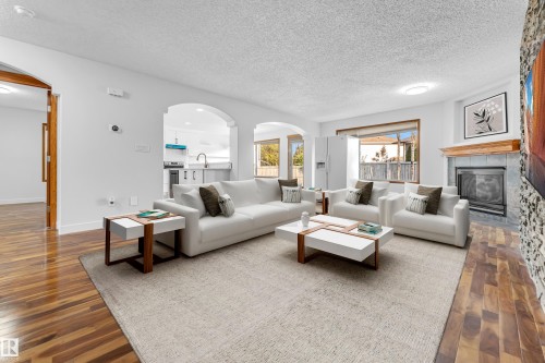 Spacious living area featuring wood-finish flooring, a tiled fireplace with a wood mantel, and large windows - 10621 175A Avenue Nw, Edmonton, AB 