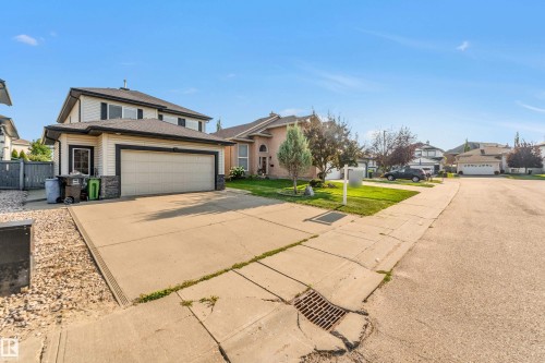 Two-story residence featuring light-colored siding with dark trim, a two-car garage, and a concrete driveway - 10621 175A Avenue Nw, Edmonton, AB 
