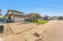 Two-story residence featuring light-colored siding with dark trim, a two-car garage, and a concrete driveway - 10621 175A Avenue Nw, Edmonton, AB 