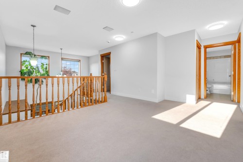 Upper-level landing featuring light-toned carpet, recessed lighting, and a wooden baluster railing - 10621 175A Avenue Nw, Edmonton, AB 