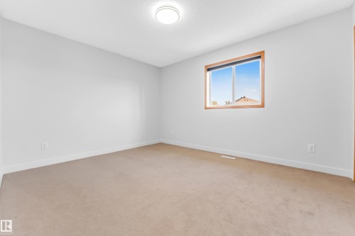 Bright room featuring neutral carpeting, white walls, and a window with wood-finish trim - 10621 175A Avenue Nw, Edmonton, AB 