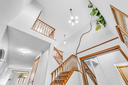 Multi-level foyer featuring soaring ceilings, a wood staircase with spindle balusters, and a recessed ceiling light - 10621 175A Avenue Nw, Edmonton, AB 