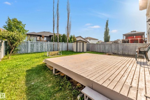 Expansive backyard featuring a large wood-finish deck, a detached storage shed, a fully fenced perimeter, and a generous grass area - 10621 175A Avenue Nw, Edmonton, AB 