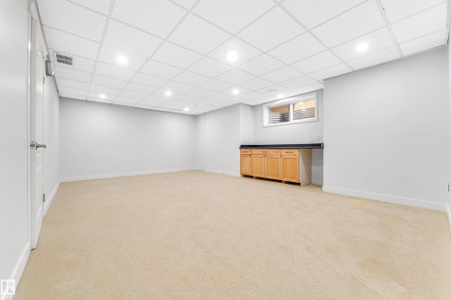 Spacious room featuring light beige carpeting, recessed lighting, and a drop ceiling - 10621 175A Avenue Nw, Edmonton, AB 