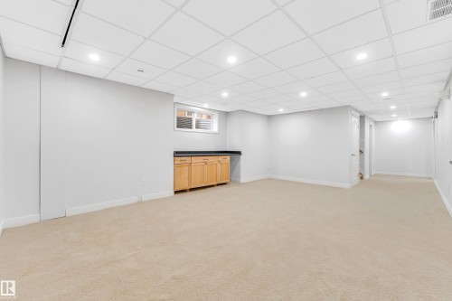 Spacious finished room featuring light beige carpeting, recessed lighting, and a drop ceiling - 10621 175A Avenue Nw, Edmonton, AB 