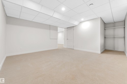 Spacious room featuring neutral carpeting, white walls, and a drop ceiling with recessed lighting - 10621 175A Avenue Nw, Edmonton, AB 