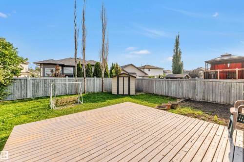 Expansive backyard featuring a spacious wooden deck, manicured lawn, full privacy fencing, and a functional storage shed - 10621 175A Avenue Nw, Edmonton, AB 