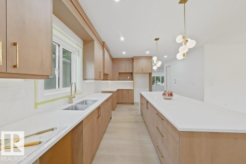 Expansive kitchen featuring a large central island, light wood-finish cabinetry with brass hardware, and white countertops - 9216 91 Street Nw, Edmonton, AB - Indoor Photo Showing Kitchen With Double Sink With Upgraded Kitchen