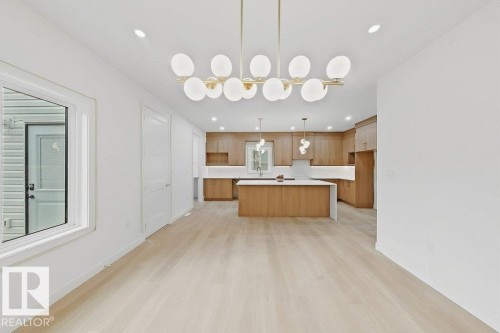 Open-concept living space featuring wood-finish flooring, recessed lighting, and a contemporary chandelier - 9216 91 Street Nw, Edmonton, AB - Indoor Photo Showing Kitchen