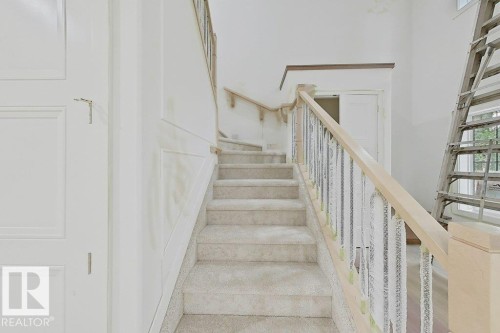 Carpeted staircase with light wood handrails and wrought iron balusters - 9216 91 Street Nw, Edmonton, AB - Indoor Photo Showing Other Room