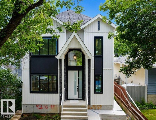 Contemporary two-story residence featuring a white vertical siding exterior with black window frames and accents - 9216 91 Street Nw, Edmonton, AB - Outdoor