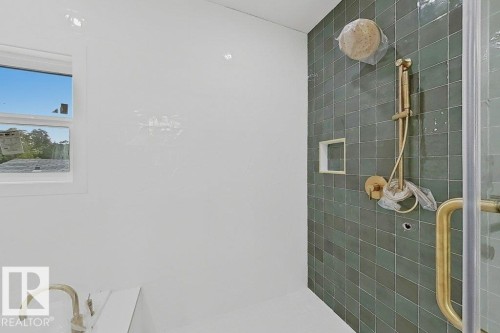 Shower with green tile surround and gold-toned fixtures, including a rain shower head and handheld sprayer - 9216 91 Street Nw, Edmonton, AB - Indoor