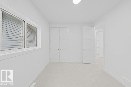 Carpeted room featuring a white interior, white trim, and a horizontal sliding window - 9216 91 Street Nw, Edmonton, AB - Indoor Photo Showing Other Room