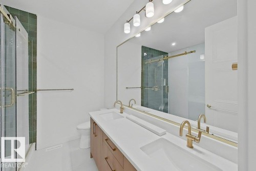 Double vanity with gold-tone hardware, white countertops, and wood-finish cabinetry - 9216 91 Street Nw, Edmonton, AB - Indoor Photo Showing Bathroom
