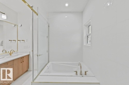 Contemporary bathroom featuring an integrated bathtub with a brushed nickel faucet, full-height white wall tiling, and a window - 9216 91 Street Nw, Edmonton, AB - Indoor Photo Showing Bathroom