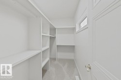 Walk-in closet featuring extensive built-in shelving, hanging rods, and a high-set window - 