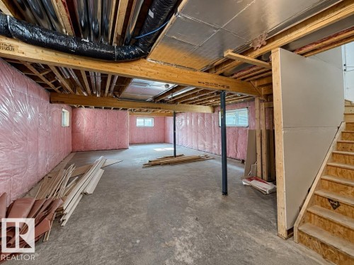 Unfinished basement showcasing exposed wood framing, concrete flooring, pink insulation, multiple windows, and a partially framed staircase - 9216 91 Street Nw, Edmonton, AB - Indoor Photo Showing Basement
