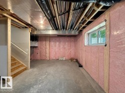 Expansive unfinished basement featuring concrete flooring, exposed ceiling joists, and insulated perimeter walls - 
