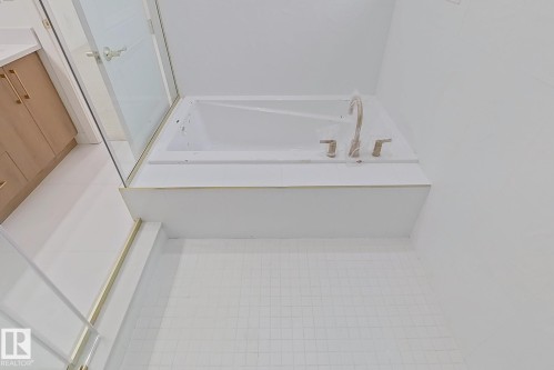 White soaking tub with brushed nickel fixtures, surrounded by white wall tiling and small white square floor tiling - 9216 91 Street Nw, Edmonton, AB - Indoor