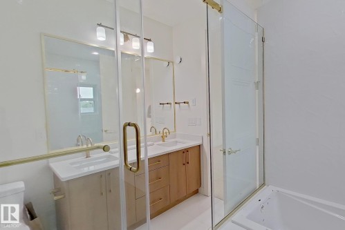 Modern bathroom featuring a dual vanity with light-tone wood cabinetry, white countertops, and gold-finish hardware - 9216 91 Street Nw, Edmonton, AB - Indoor Photo Showing Bathroom