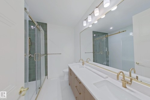 Contemporary bathroom featuring a double vanity with stone countertops and brass fixtures - 9216 91 Street Nw, Edmonton, AB - Indoor Photo Showing Bathroom