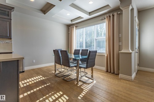Recessed lighting, tray ceiling details, wood-finish flooring, a large window with blinds, and decorative column accents - 233 Hawks Ridge Boulevard Nw, Edmonton, AB 