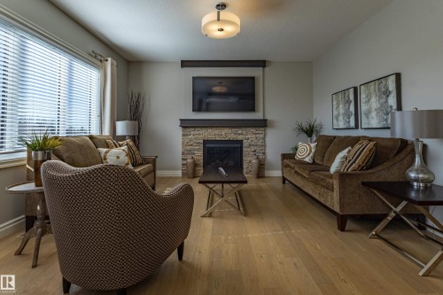 Stone-faced fireplace with wood mantel, wood-finish flooring, recessed lighting, and large windows with blinds - 233 Hawks Ridge Boulevard Nw, Edmonton, AB 