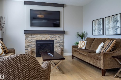 Stone-clad fireplace with a dark wood-finish mantel and integrated media area - 233 Hawks Ridge Boulevard Nw, Edmonton, AB 