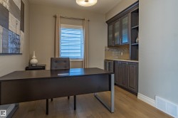 Built-in cabinetry with glass-front uppers and open shelving, tile backsplash, wood-finish flooring, and window with blinds - 