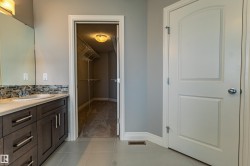 Vanity with a single basin sink, mosaic tile backsplash, and dark wood-finish cabinetry - 