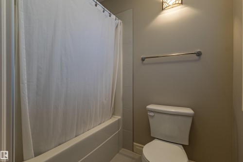 Bathroom featuring a built-in bathtub, a toilet, a wall-mounted towel bar, and an overhead light fixture - 233 Hawks Ridge Boulevard Nw, Edmonton, AB 