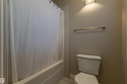 Bathroom featuring a built-in bathtub, a toilet, a wall-mounted towel bar, and an overhead light fixture - 
