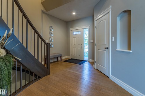 Wood-finish flooring, staircase with dark wood railing, white paneled doors, and recessed wall niche - 233 Hawks Ridge Boulevard Nw, Edmonton, AB 