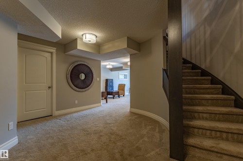 Curved staircase with carpeted treads, neutral carpet flooring, and a paneled interior door - 233 Hawks Ridge Boulevard Nw, Edmonton, AB 
