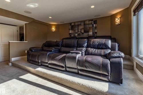 Carpeted tiered flooring, recessed ceiling lighting, wall-mounted sconce lighting, and a white interior door - 233 Hawks Ridge Boulevard Nw, Edmonton, AB 