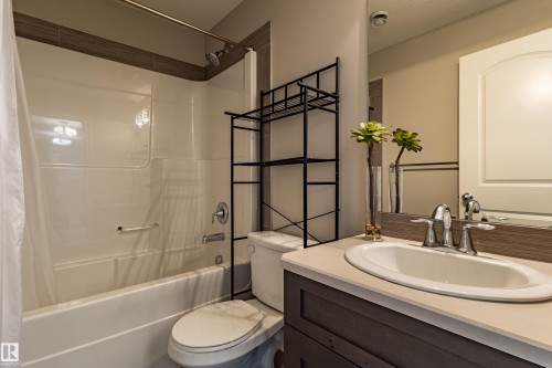 Tub and shower combination with chrome fixtures, vanity with integrated sink, and wood-finish cabinetry - 233 Hawks Ridge Boulevard Nw, Edmonton, AB 