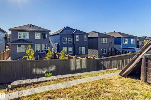 Sloped backyard with wood-toned retaining wall and concrete step path - 233 Hawks Ridge Boulevard Nw, Edmonton, AB 