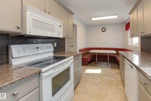 Kitchen featuring granite countertops, a built-in microwave, an electric range, and light-toned cabinetry - 3421 135A Avenue Nw, Edmonton, AB 