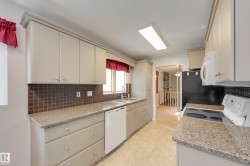 Kitchen featuring light-toned cabinetry, speckled countertops, and a tiled backsplash - 