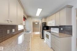 Kitchen featuring light-toned cabinetry, granite-finish countertops, square tile backsplash, and tile flooring - 