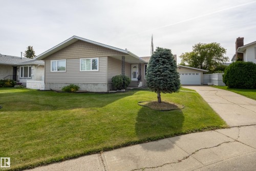 Exterior featuring light-colored siding, shake shingles, and a well-maintained lawn - 3421 135A Avenue Nw, Edmonton, AB 